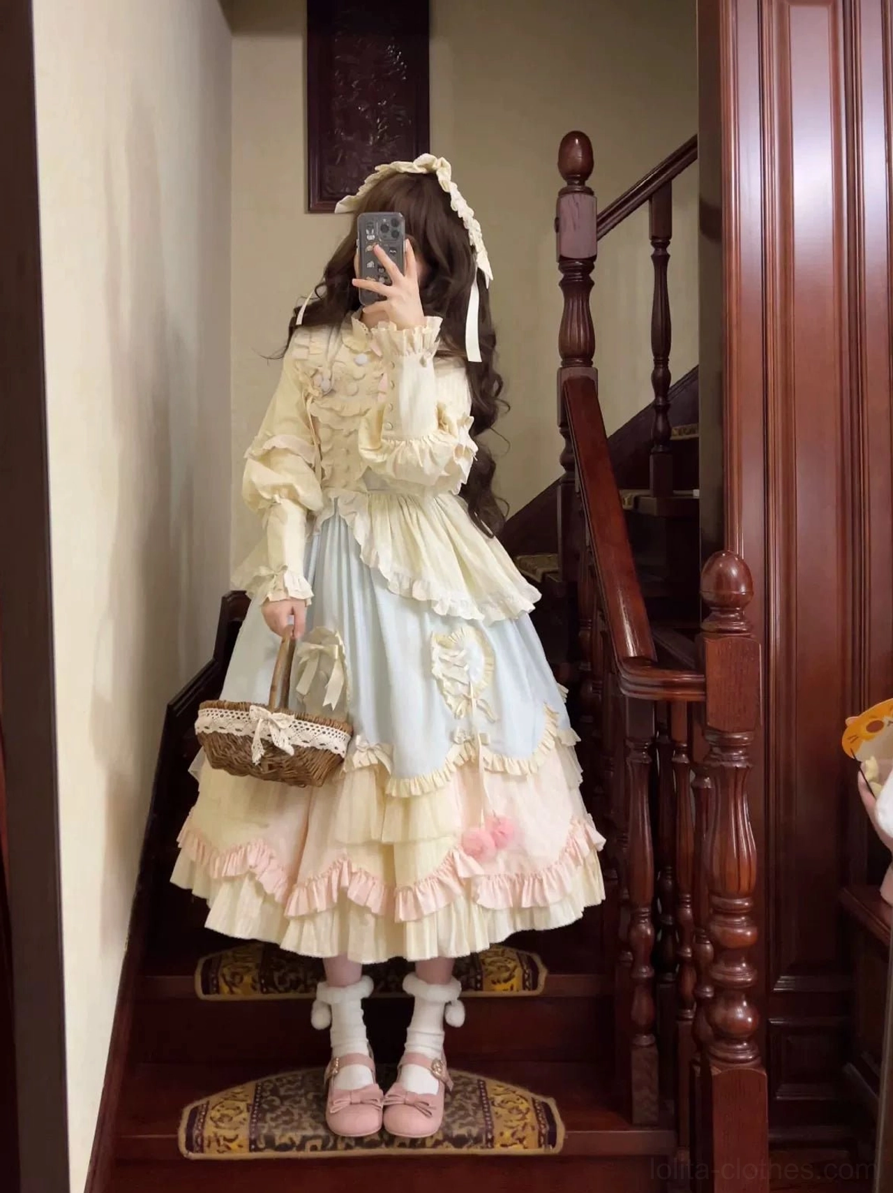 Full-body front view of pastel sweet lolita OP dress on wooden stairs carrying wicker picnic basket frilled ankle socks pink flats classic lolita silhouette
