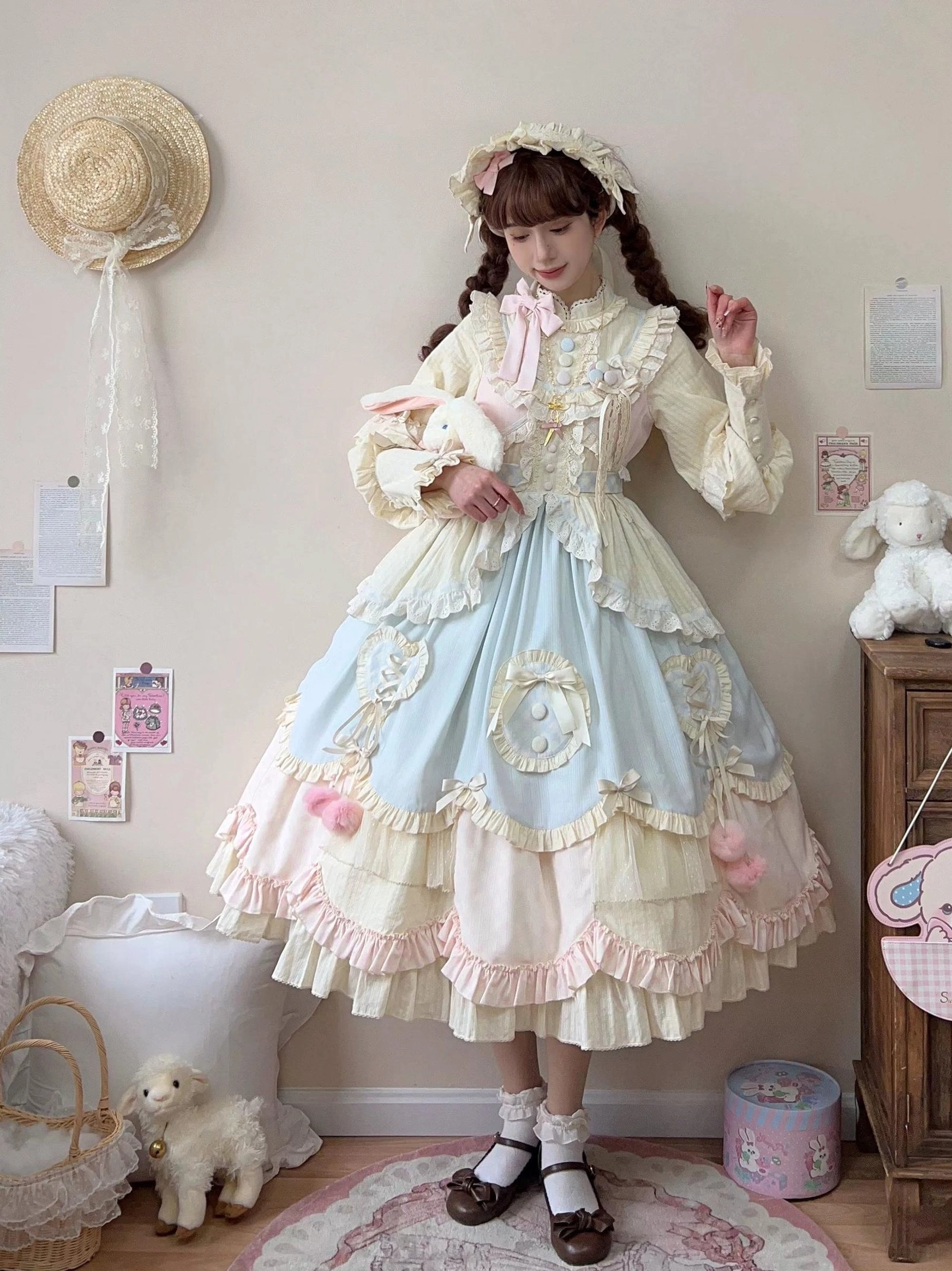 Oblique full-body view of pastel sweet lolita OP dress with straw hairband heart-shaped applique decorations on skirt color-blocked ruffled silhouette holding plush rabbit doll