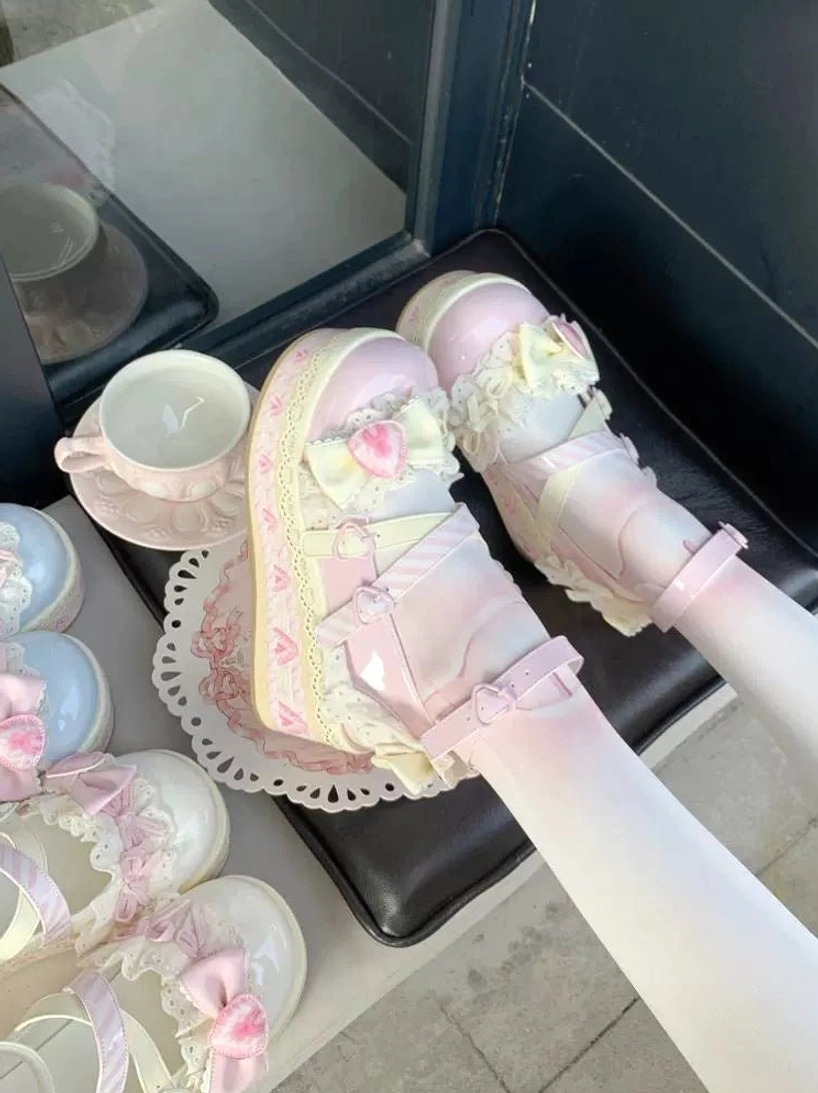 All-pink sweet lolita platform shoes top-down on-foot view with ruffled lace bow and heart flower decoration multiple pairs with candles on black leather seat