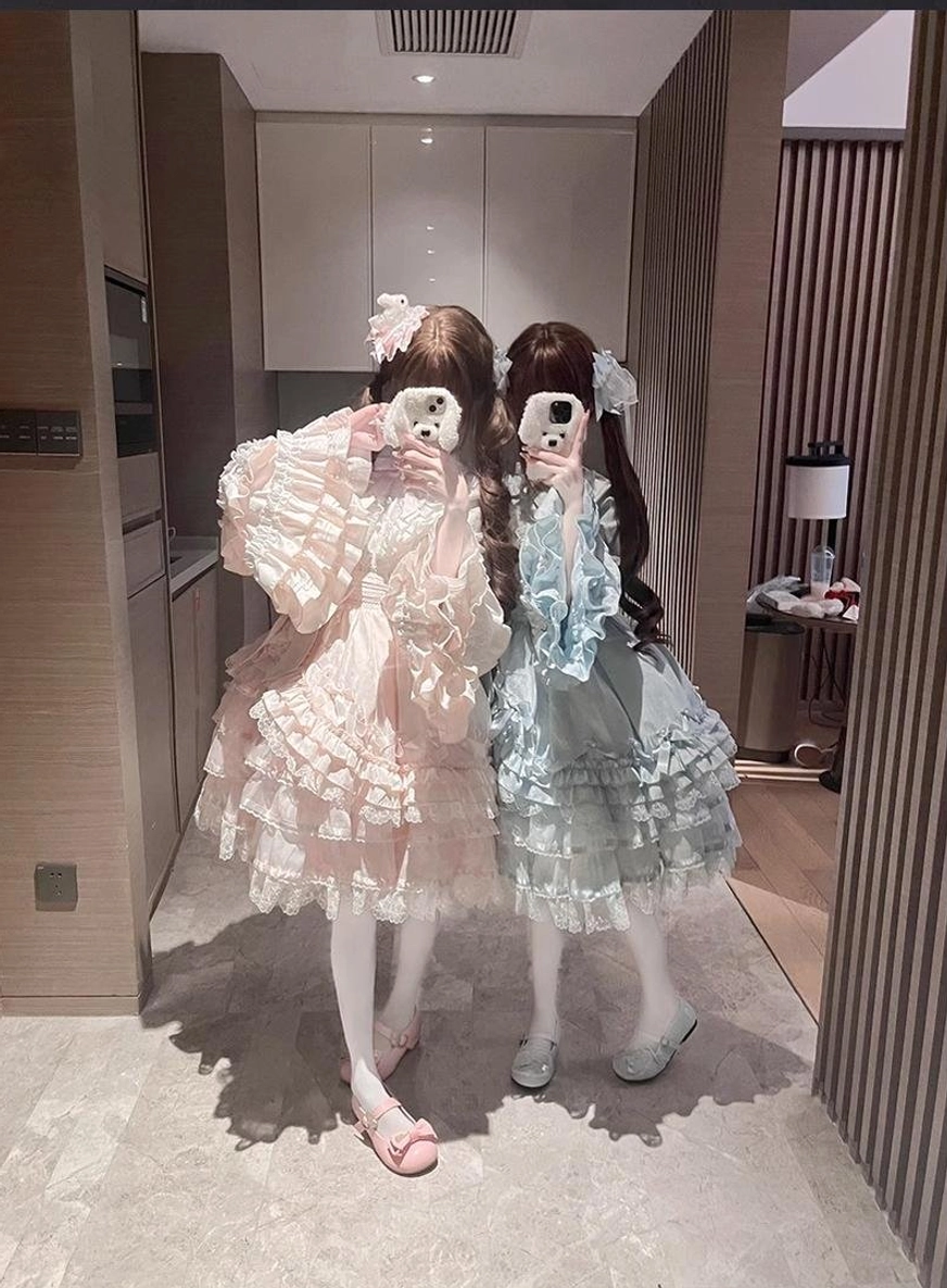 Two sweet lolita OP dresses full-body mirror selfie view indoor home corridor one pastel pink one sky blue tiered ruffled lace skirts princess sleeves matching coordinates