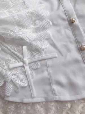 Close-up detail of white lace ruffled cuff with cross-shaped leather strap embellishment and gold decorative button on stand collar chiffon blouse