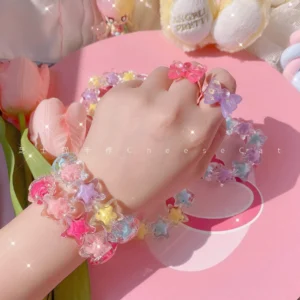 Close-up overhead view of female hand and wrist wearing star-shaped beaded Lolita bracelet and matching star rings, showcasing mixed pink blue purple and yellow translucent acrylic tones with elastic beaded design