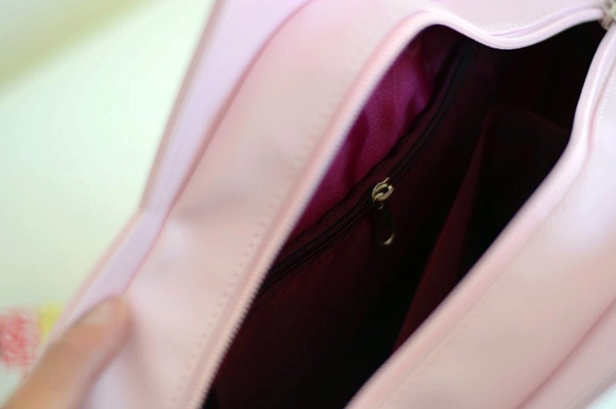 Interior close-up view of star Lolita bag showing dark purple satin lining, built-in zippered pocket for storage, and pink exterior leather detail