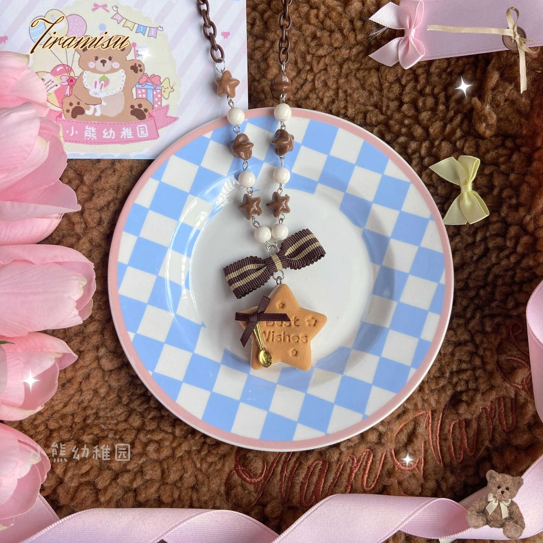 Flat lay overhead shot of star and round cookie lolita hair clips and beaded chain accessories on blue-white checkered ceramic plate featuring brown striped bows and detailed biscuit charms with mixed brown and white beads