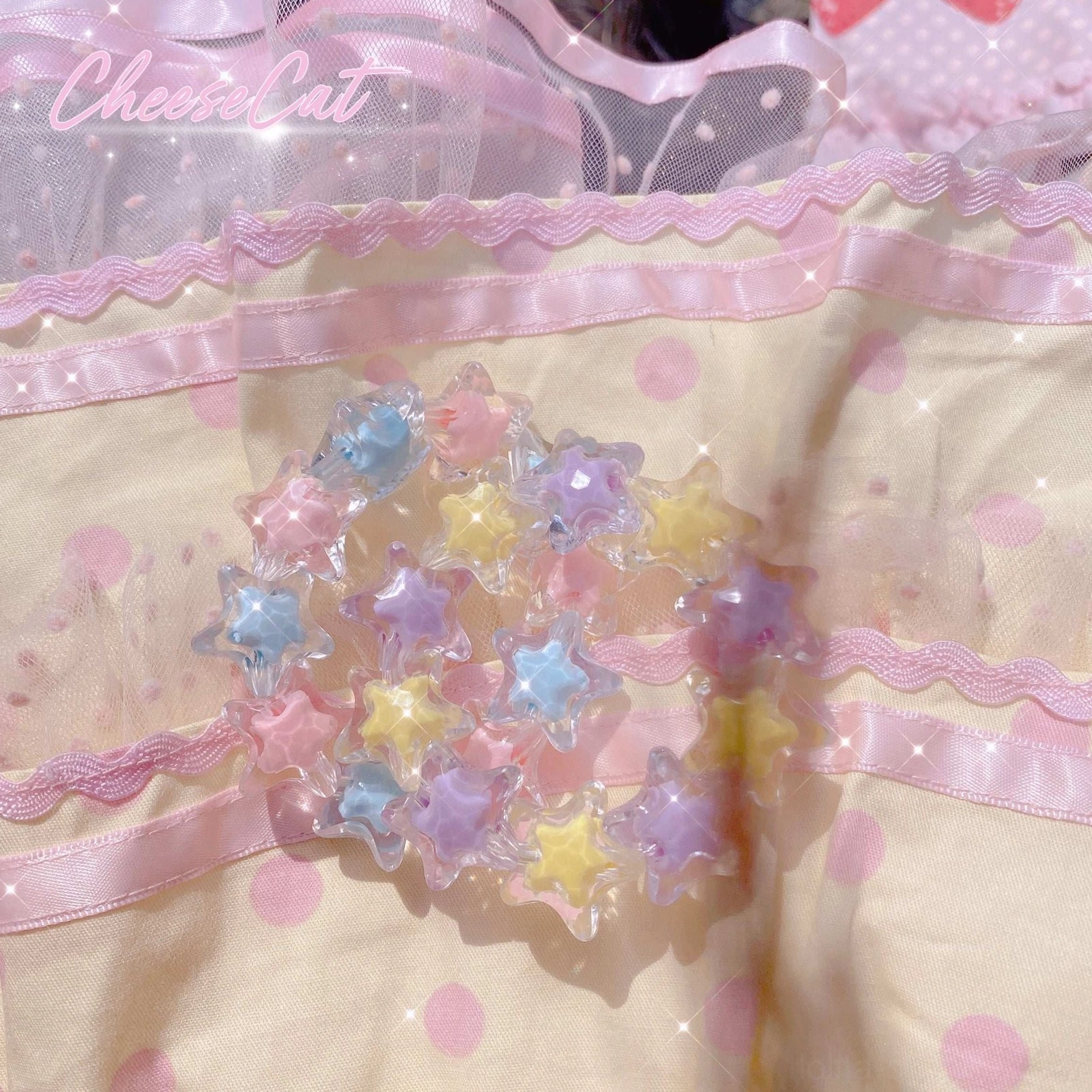 Close-up flat lay display of star-shaped beaded Lolita bracelet with pastel rainbow star acrylic beads featuring glittery decorative finish, arranged on pink polka-dot Lolita dress fabric background