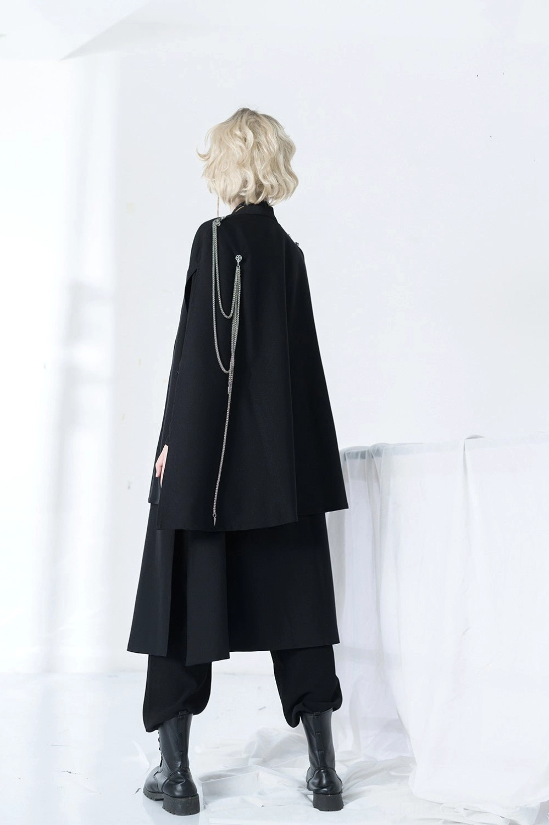 Model wearing complete Stars Change Ouji lolita military set with black cape flowing silver chains full body rear shot white studio backdrop