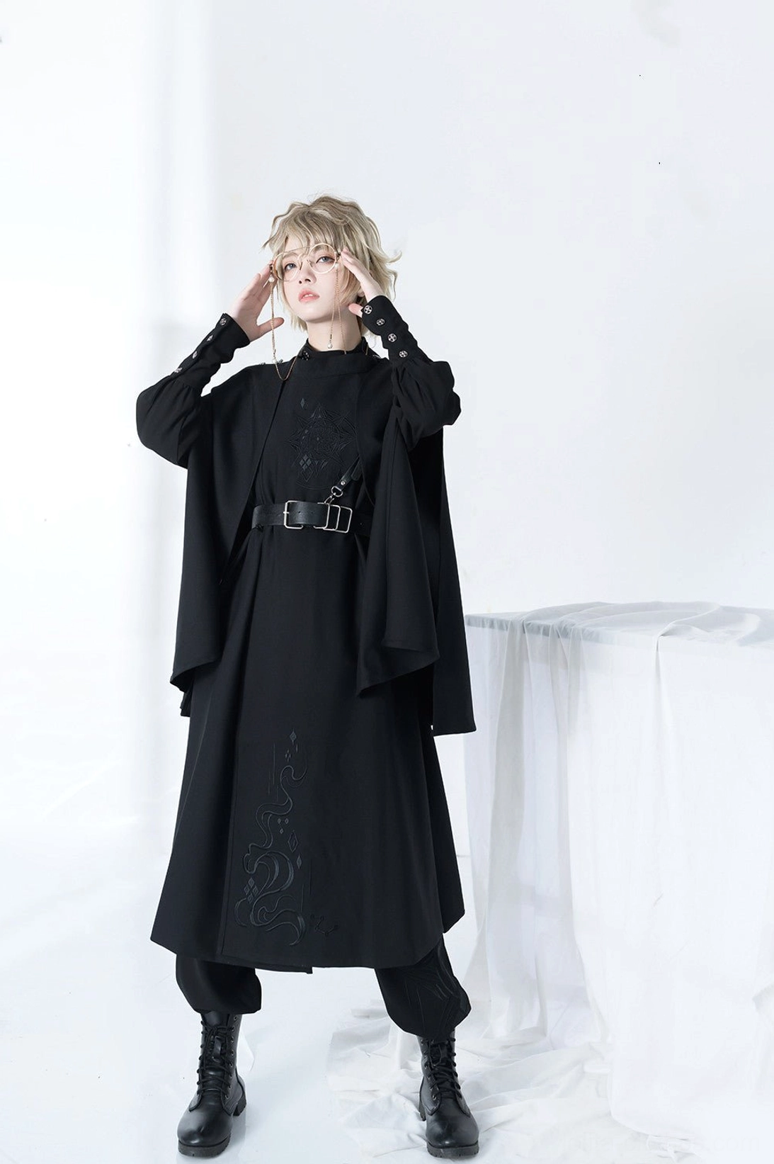 Female model in Stars Change Ouji lolita military fashion full body front shot black cape silver chain accents fitted waist belt tunic top