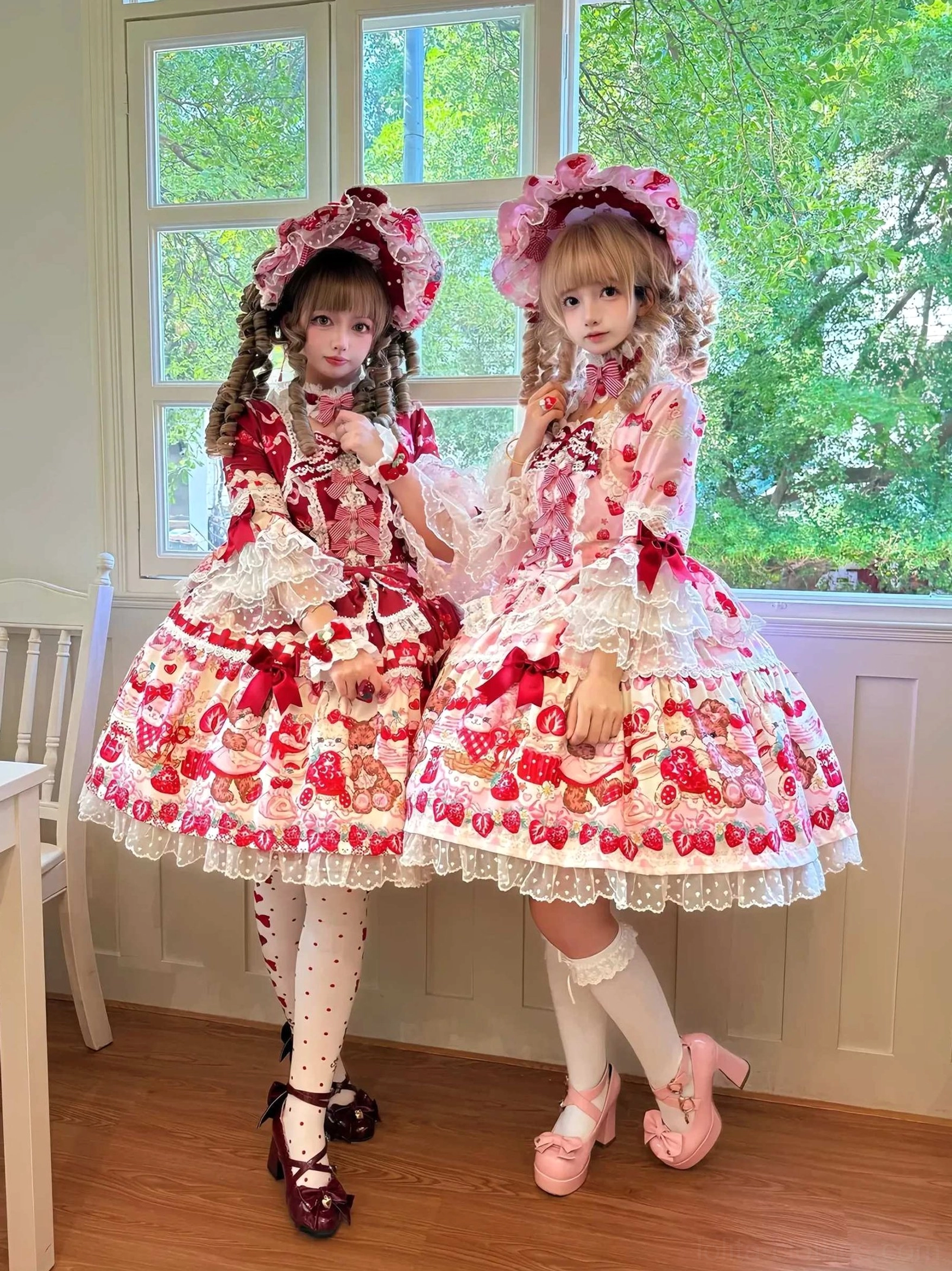Two lolita models wearing matching strawberry bear sweet lolita OP dresses with hime sleeves, showcasing front coordinate view with bonnets, Mary Jane shoes, and tights