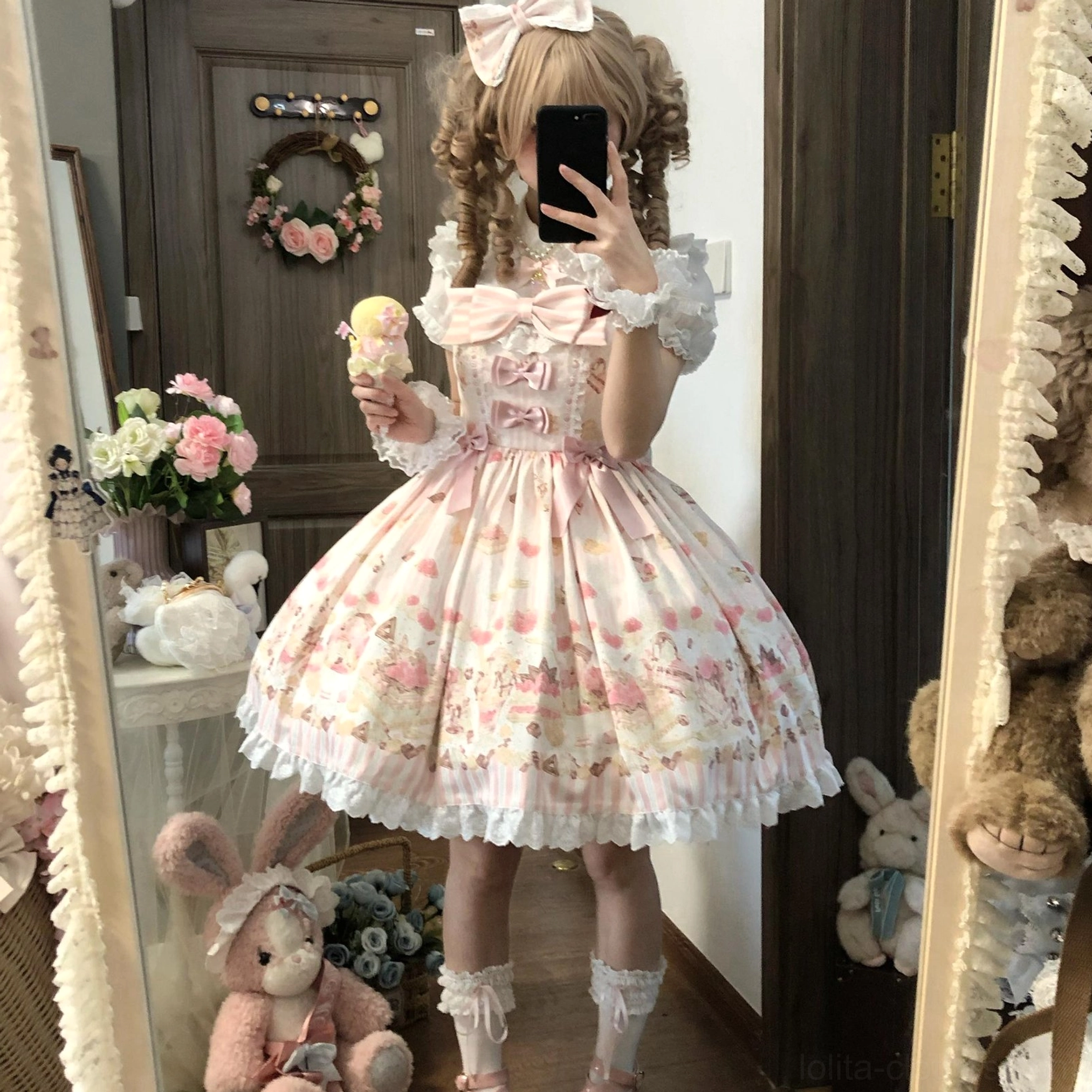 Sweet Lolita model in Iced Strawberry Cheese JSK dress holding ice cream prop brown curly twin-tail hair pink bow accessories frilly lace socks bedroom photoshoot