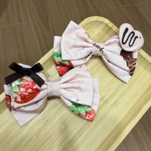 Pink strawberry chocolate printed hair clips pair with bows wooden tray flat lay lolita accessory