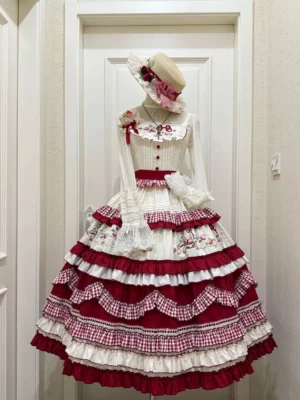 Red and cream country lolita jumper skirt dress with strawberry embroidery tiered ruffle skirt and gingham trim front view on mannequin