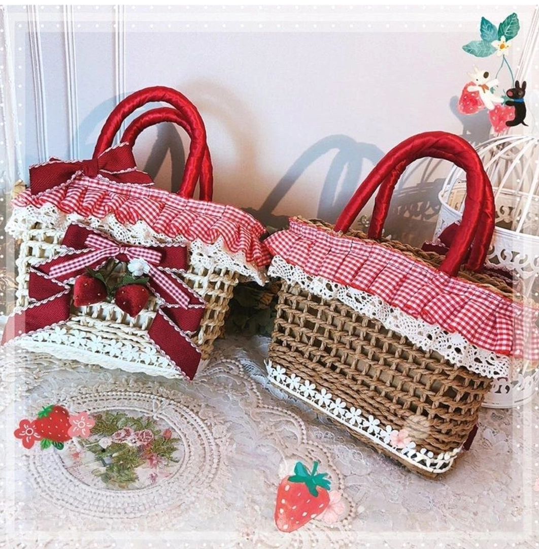 Beige and brown strawberry gingham Country Lolita straw tote bags displayed side by side with red handles and fruit decorations