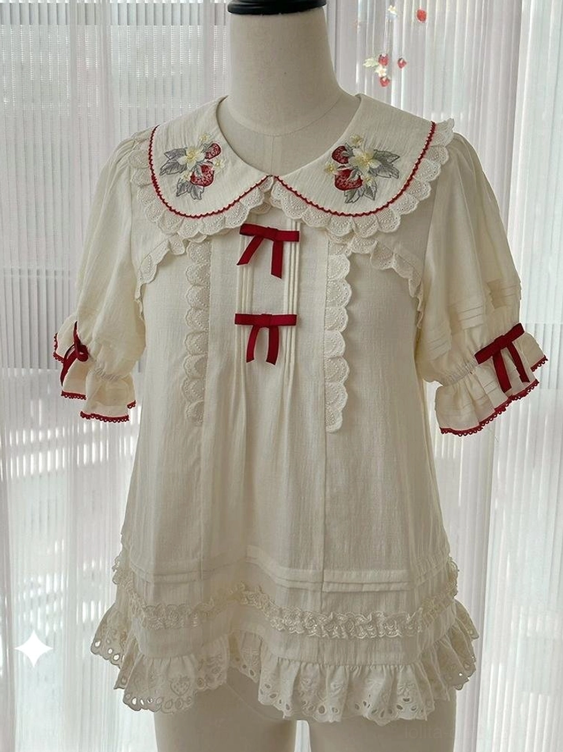 Strawberry embroidered ivory sweet lolita blouse with Peter Pan collar and detachable red ribbon bows displayed on dress mannequin full front view