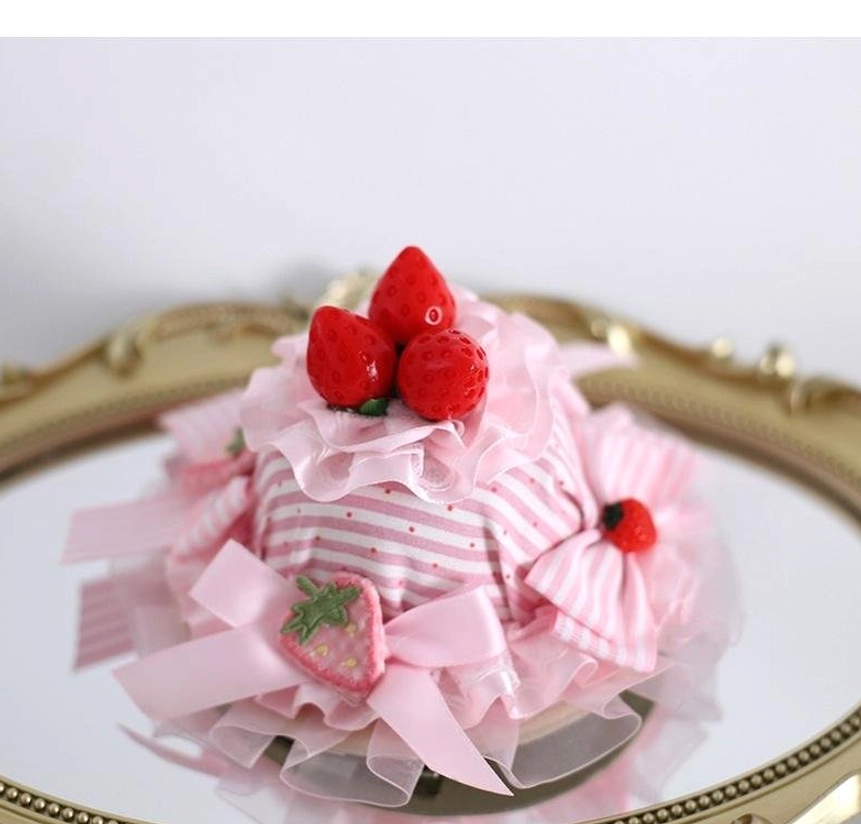 Strawberry lolita mini cake hat decorator with pink ruffled layered fabric striped center multiple pink bows and strawberry charms flat lay