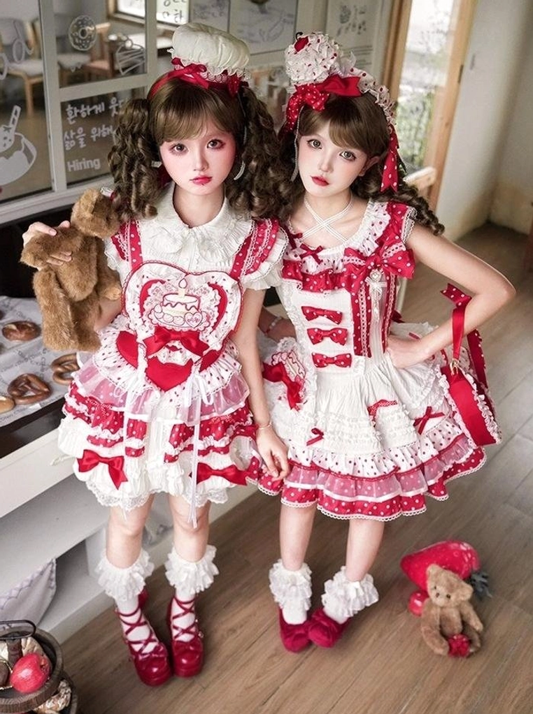 Twin models wearing strawberry-themed red and white sweet lolita outfits in retro bakery shop setting with heart bear print and tiered ruffled skirts