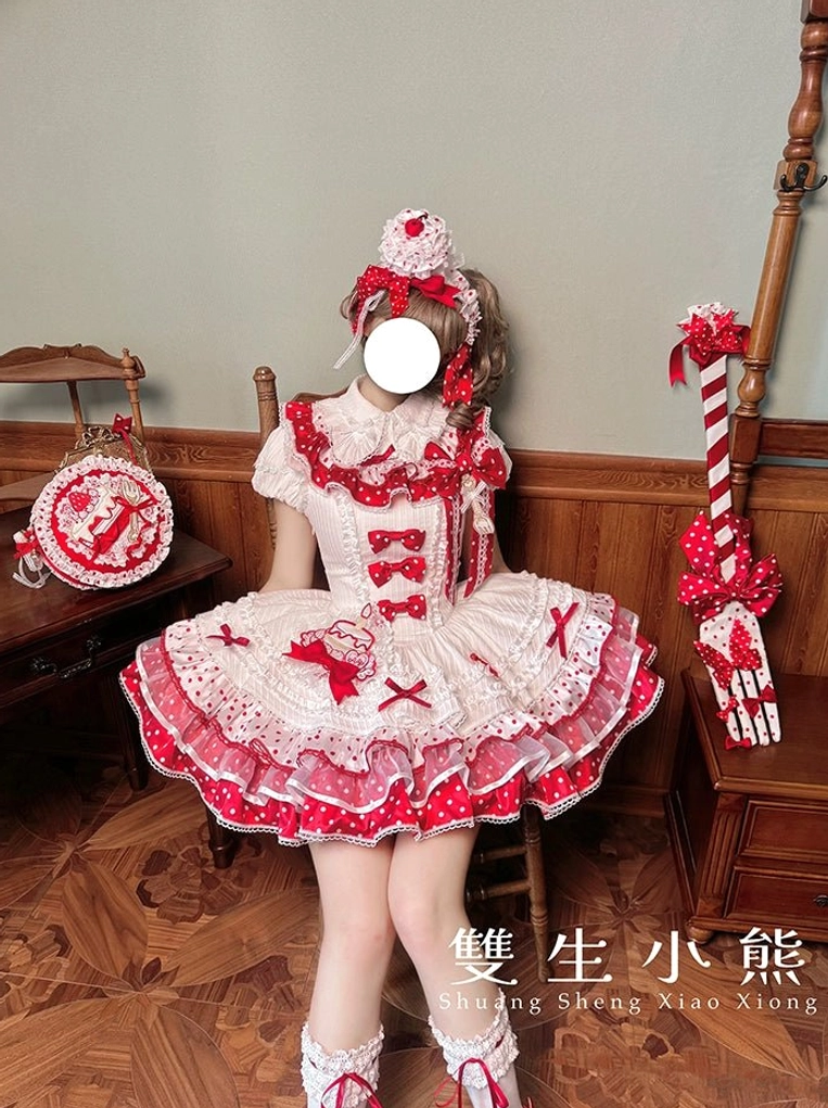 Strawberry-themed sweet lolita dress full front view with heart bear print, red lace trim, tiered ruffled skirt, matching hair accessory and small handbag on wooden floor