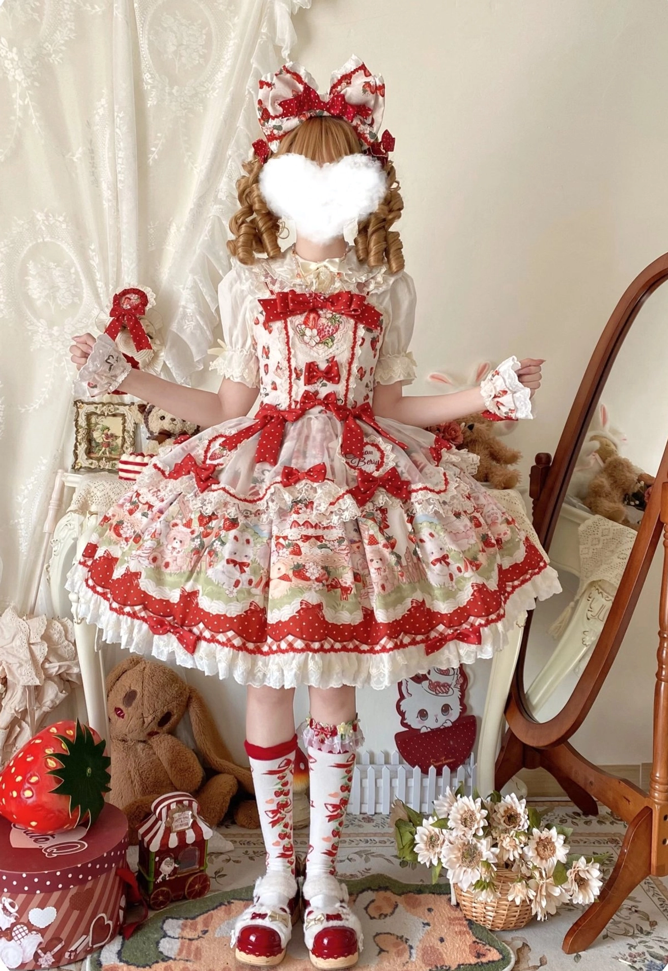 Strawberry sweet Lolita JSK dress with big hair bow back full-body view, holding striped gift box prop, showing corset waist design, consistent strawberry print pattern throughout, indoor mirror and plush toy background