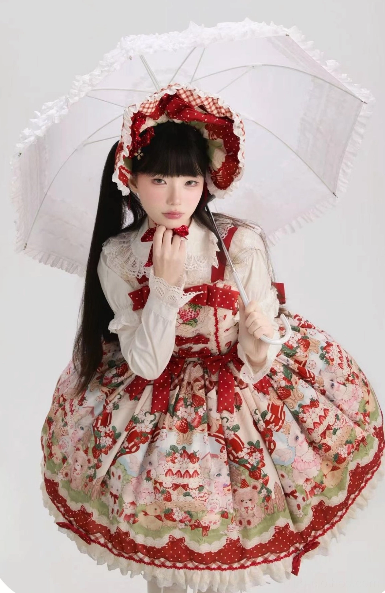 Strawberry sweet Lolita JSK dress with matching bonnet front medium shot, held with plush rabbit prop, featuring red wrist cuffs, bowknot necktie, embroidered strawberry details, styled with twin hairstyle on white background