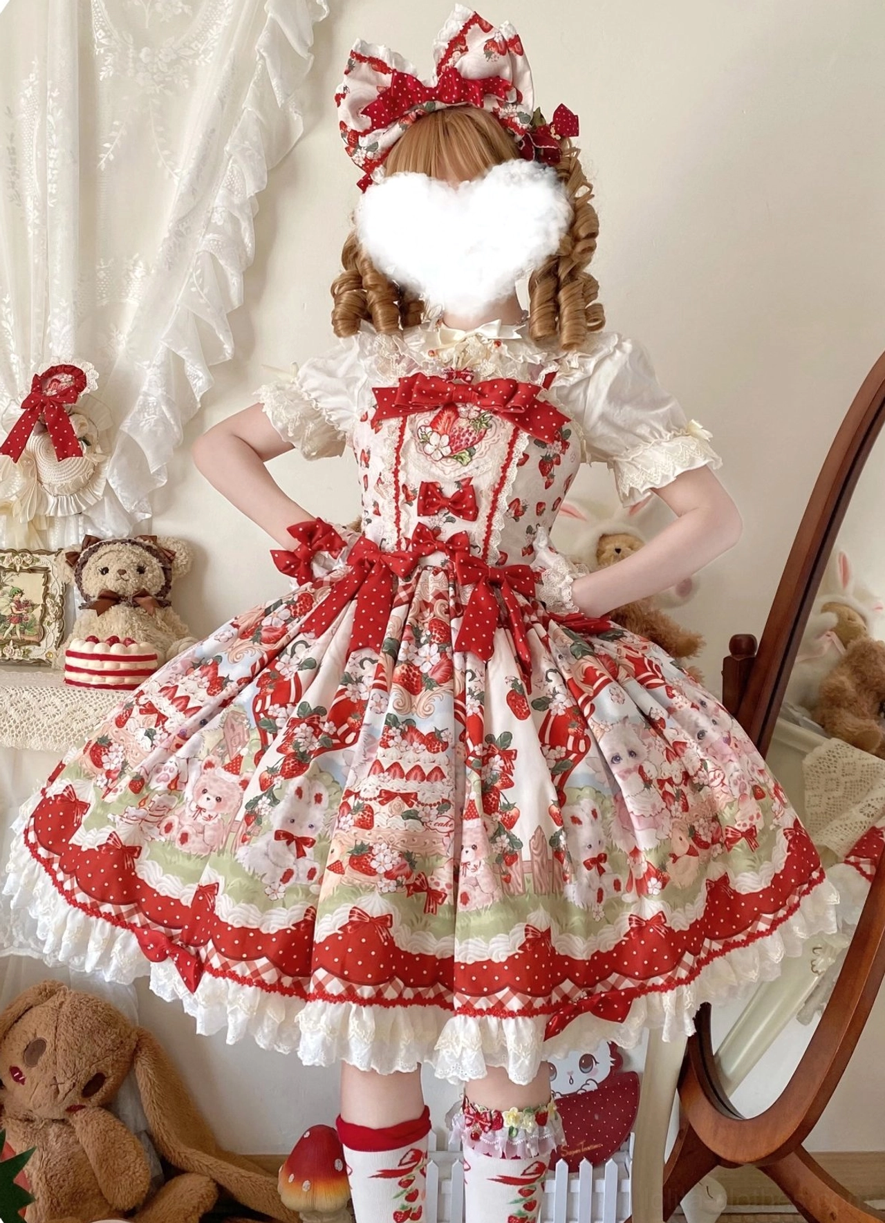 Strawberry sweet Lolita JSK dress with big hair bow front three-quarter view, hands on hips pose, showing wide flared A-line silhouette, red waist bow decoration, scalloped lace hem, plush toy decor background