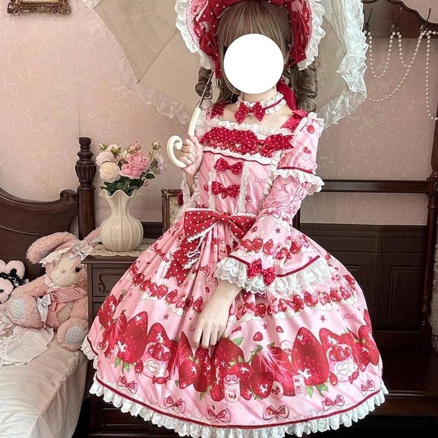 Strawberry sweet lolita OP dress front full view worn on model in vintage bedroom with pink base fabric red strawberry print lace ruffled trims and bow decorations
