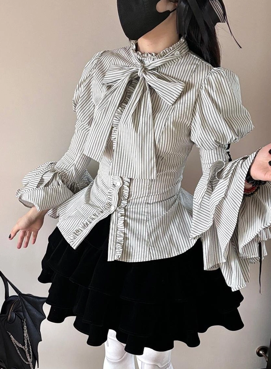 Side view of person wearing striped Gothic Lolita blouse with ruffled bell cuffs, fitted waist and fine stripe print, paired with black velvet mini skirt and white stockings
