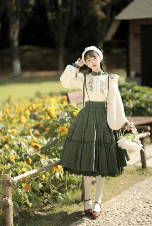 Chinese style Lolita blouse and suspender skirt set full body outdoor front view in sunflower field with model wearing cream embroidered stand collar blouse and dark green tiered ruffle skirt