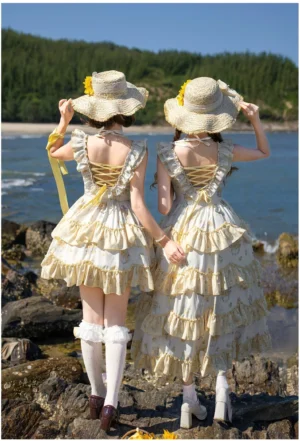 Back view of sunflower lolita jumper skirt showcasing crisscross lace-up closure and layered ruffled tiered hemline on rocky coastal beach