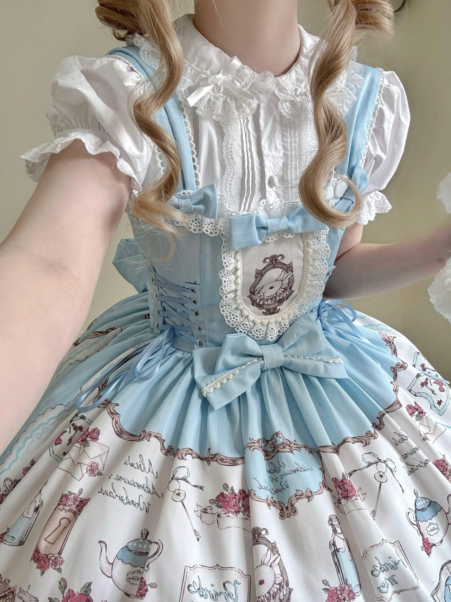 Sweet lolita coordinate set featuring blonde model wearing white ruffled inner blouse with peter pan collar layered under sky blue corset bodice with oversized bow and tea-party themed print skirt