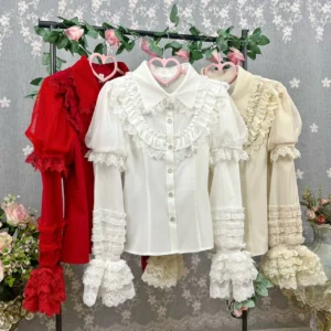 Sweet lolita blouse collection in multiple colors including cream white beige and red with peter pan collar front button closure and layered ruffled lace sleeve trim displayed on hanging dress forms with floral backdrop