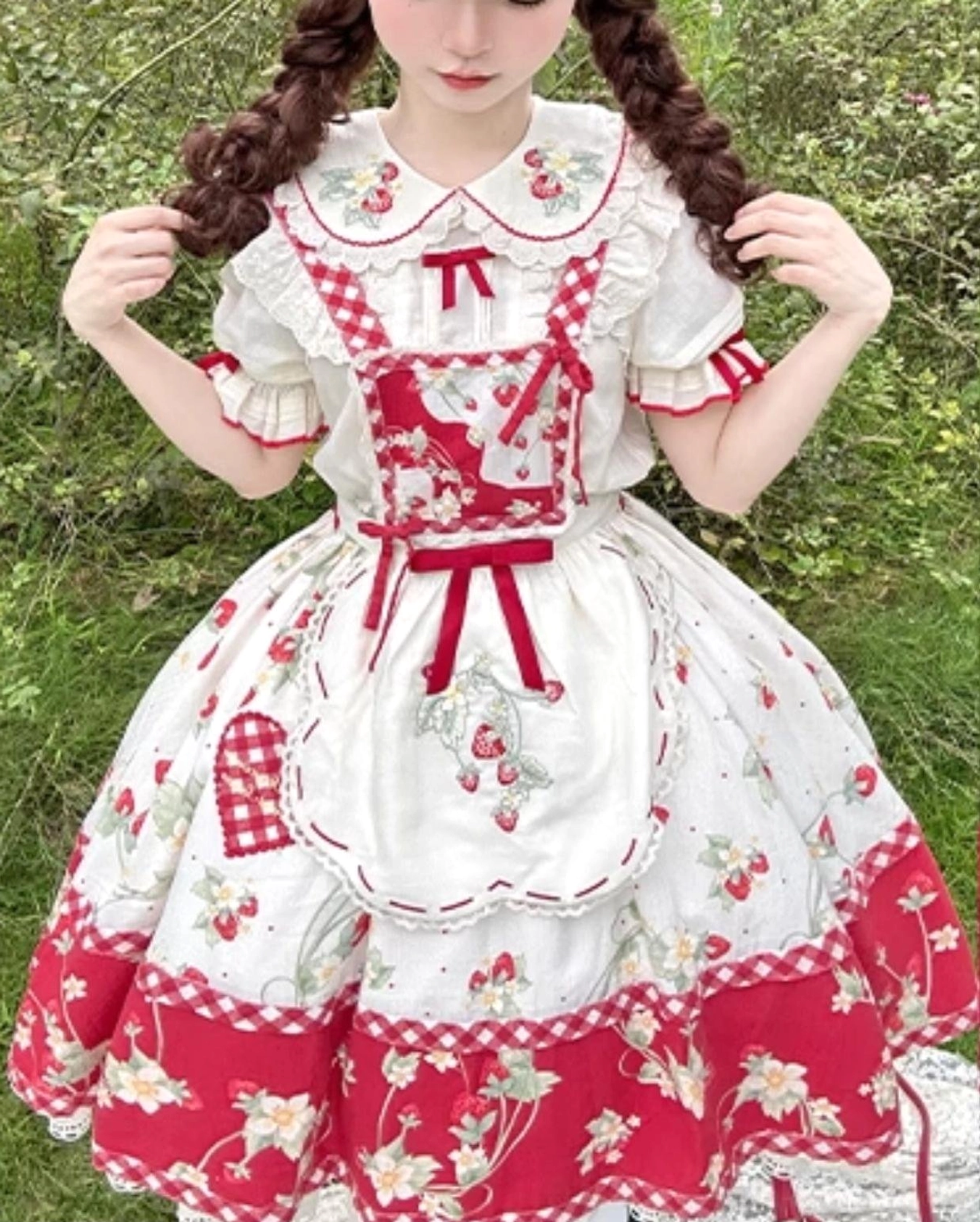 Removable red ribbon bow detail on sleeve of ivory strawberry sweet lolita blouse showing attachment and decorative aesthetic with embroidered collar