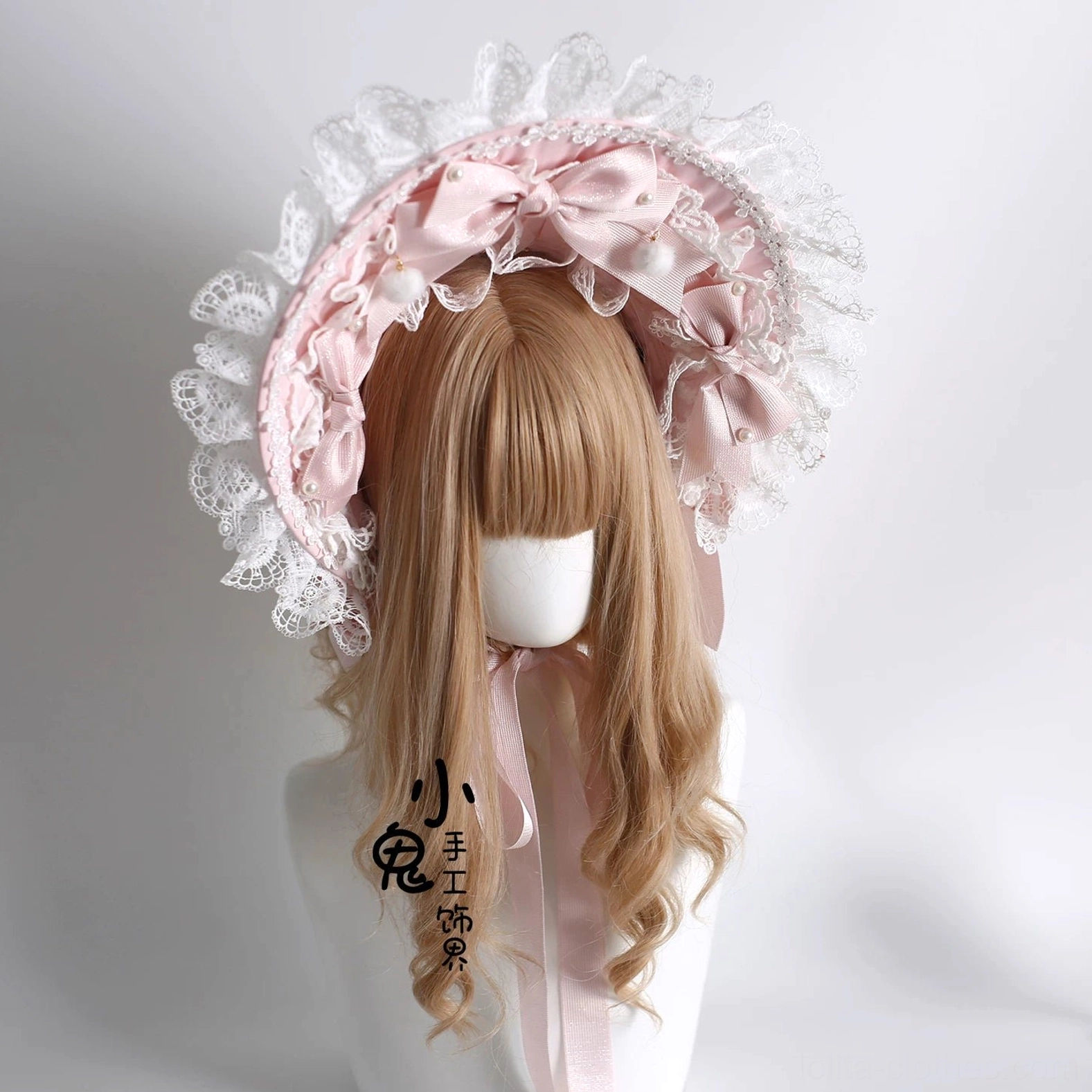 Sweet Lolita bonnet headdress front view on blonde wig mannequin, featuring pink satin bows, ruffled white lace trim, matching neck ribbon, and pom-pom accents