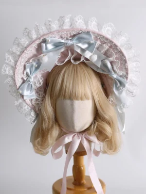 Sweet Lolita pastel pink and white ruffled lace bonnet headdress with sky blue satin bows worn on blonde bob wig mannequin, front full view showcasing embroidered lace details