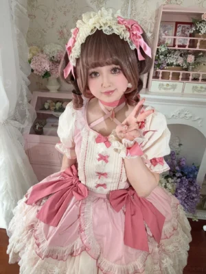 Sweet lolita bow brooch with dusty rose satin and heart crystal center, displayed on vintage pink dollhouse shelf with matching cream and pink classic lolita princess dress and hair accessories in background