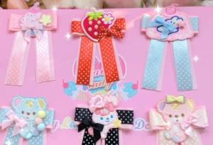 Sweet Lolita bow hair clip pins collection flat lay display showing multiple pastel colored corsage accessories with polka dot ribbons bear and strawberry embroidery patches on pink branded background