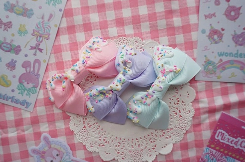 Handmade sweet lolita bow hair clips in pink lavender and light blue with cream frosting overhead flat lay