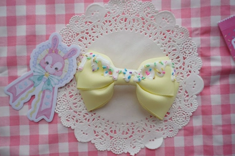 Handmade sweet lolita bow hair clip in cheerful yellow with cream frosting and colorful sprinkles close-up detail view