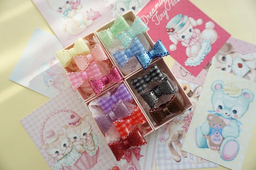 lolita bow hair clips arranged in split plastic storage trays angled overhead view full color variants
