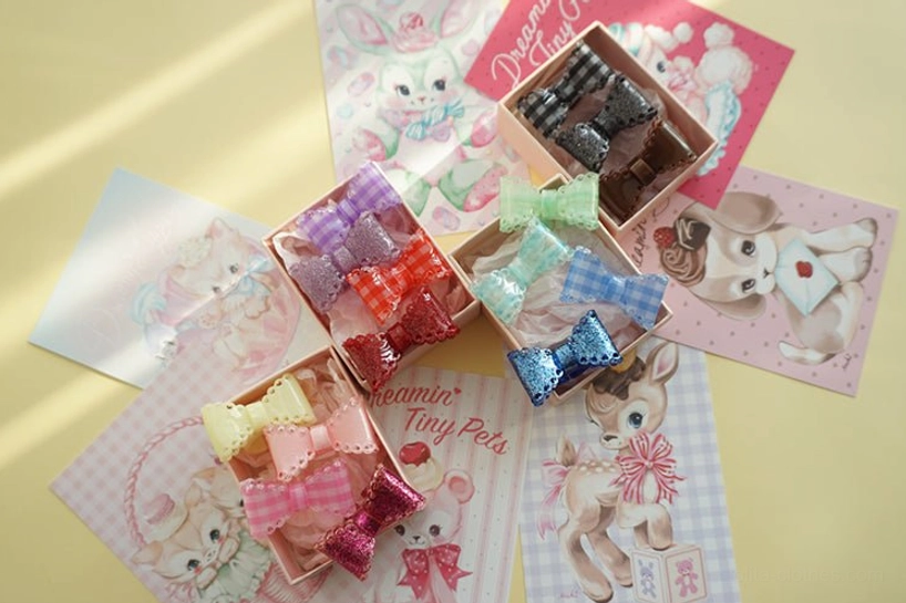 scattered gingham bow hair clips with glitter ribbon trims on yellow backdrop cute kawaii animal postcards