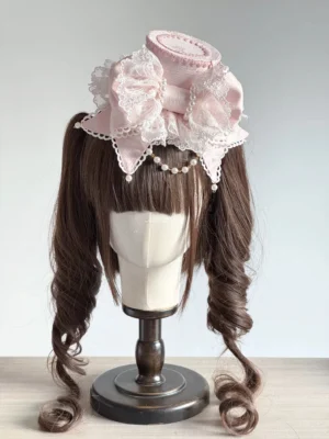 Sweet Lolita pink bowknot top hat with pearl forehead chain and lace trim displayed on twin tail curly wig mannequin front view