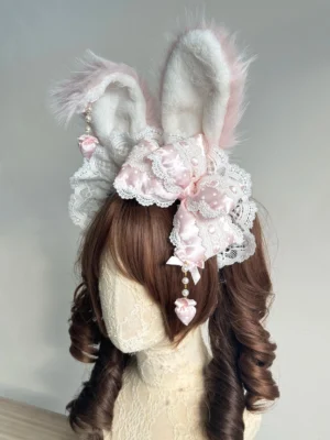 Sweet lolita bunny ear headdress with white-pink fuzzy ears and pink polka dot bow with lace frills, front three-quarter view on mannequin with brown curly twin tails wig, pearl chain heart pendant detail