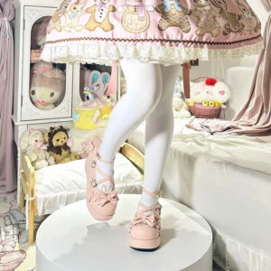 Sweet Lolita platform Mary Jane shoes with bunny ear accents and bow ornament worn indoors, pastel peach pink glossy patent leather finish, cozy bedroom setting with plush toys