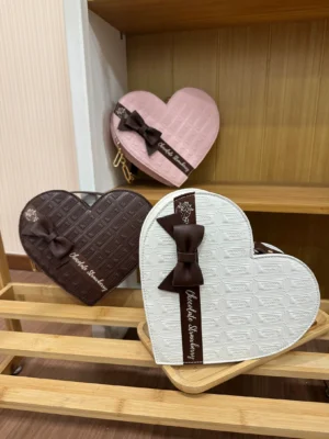 Sweet Lolita heart-shaped chocolate tote bags collection in multiple color variations displayed on wooden shelf featuring quilted embossed texture and bow decorations