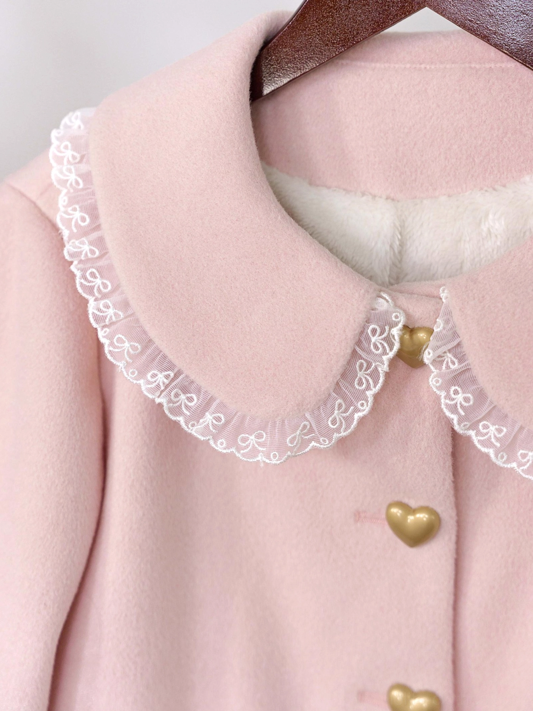 Sweet lolita fleece coat close-up detail showing embroidered heart pockets with delicate lace trim and satin ribbon bow neck decoration