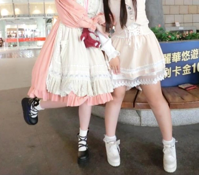 Full-body outdoor photo of two Lolita models wearing sweet Lolita coordinates with Mary Jane platform shoes—one in black, one in white—at mall location