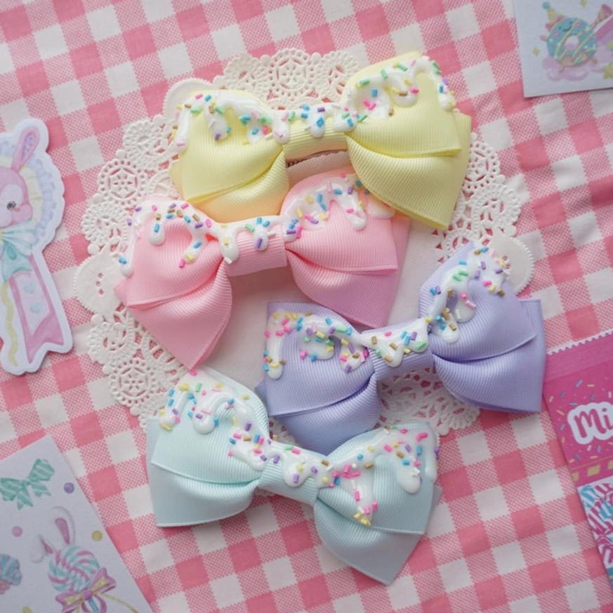 Handmade sweet lolita cream cake bow hair clips overhead flat lay featuring four pastel color variants on pink checkered background