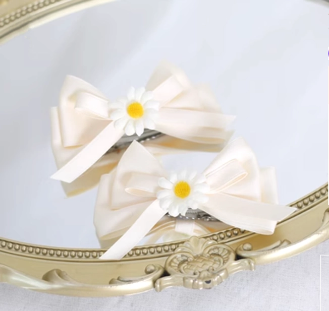 Pair of daisy satin bow sweet lolita hair clips with cream flowers displayed on vintage gold mirror tray