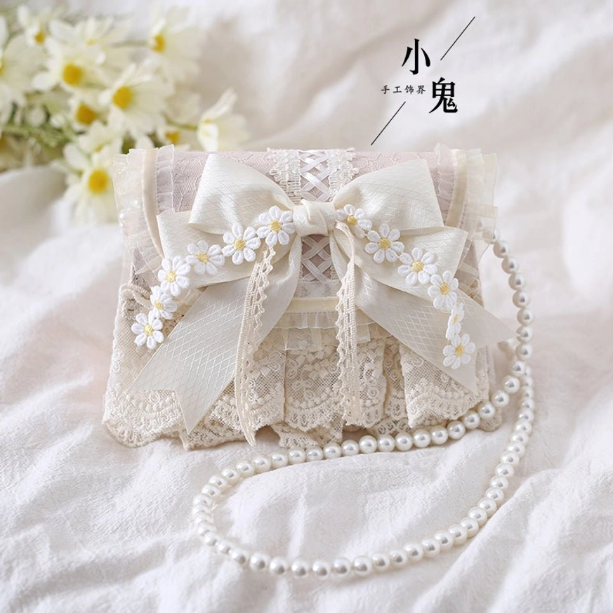 Sweet lolita daisy handbag with ruffled lace trim and long pearl chain strap, front flat view on floral white cloth