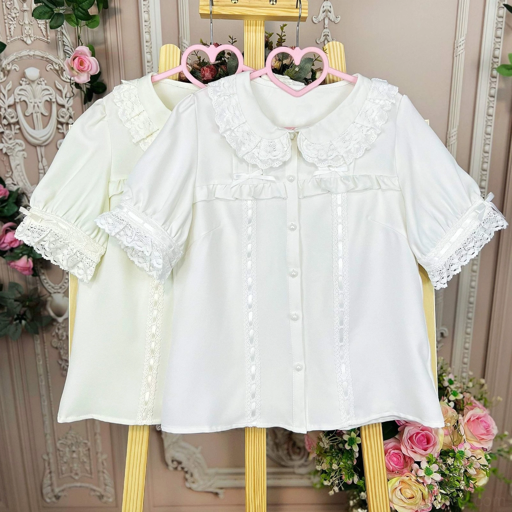 Two milky white sweet lolita doll collar blouses with ruffled lace trim and pearl buttons displayed on vintage heart hangers against European carved pink floral wall with rose vine decorations