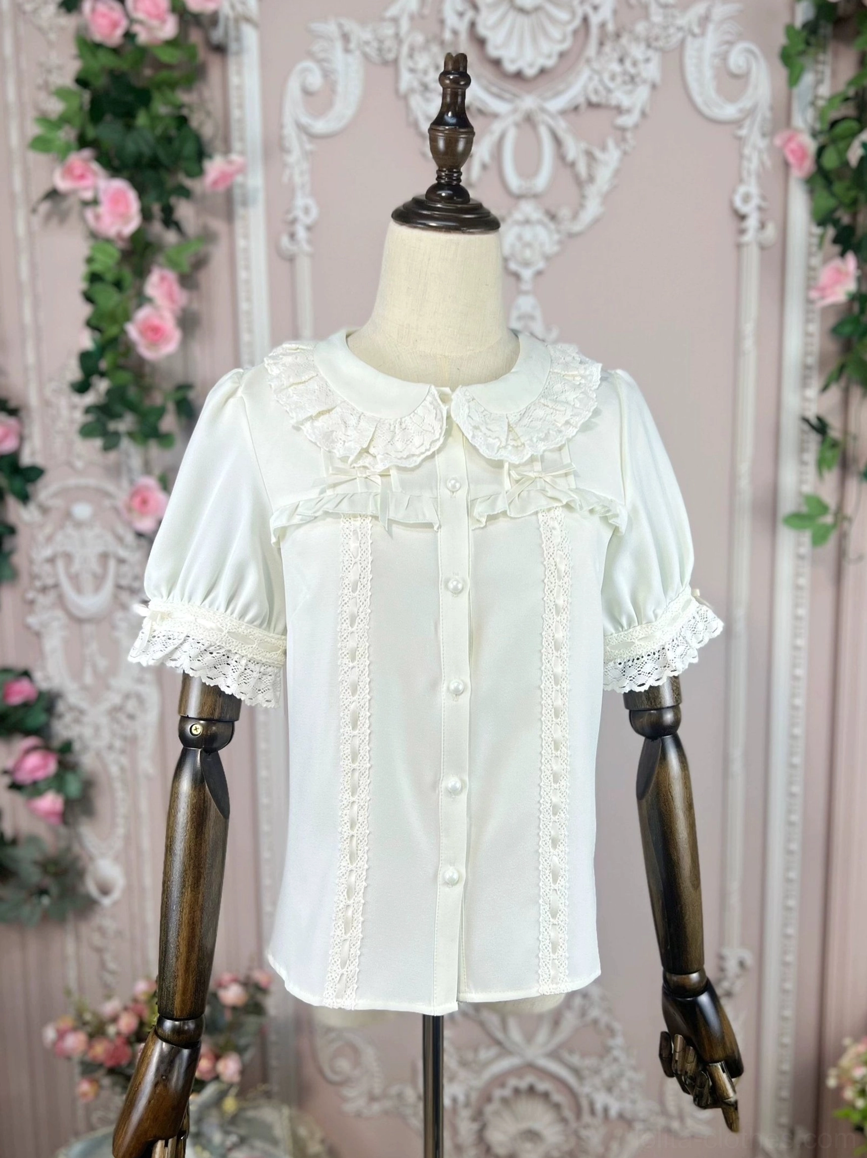 Lolita shirt on mannequin in left front three-quarter view displaying complete lace details on collar and puff sleeves with neat button arrangement and European rose vine background
