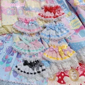 Overhead flat lay display of six assorted sweet lolita gingham lace wrist cuffs in multiple colorways including pink, red, yellow, blue, mint green and black plaid patterns with scalloped white lace trim and layered decorative bows arranged on pastel candy-patterned lolita dress fabric background